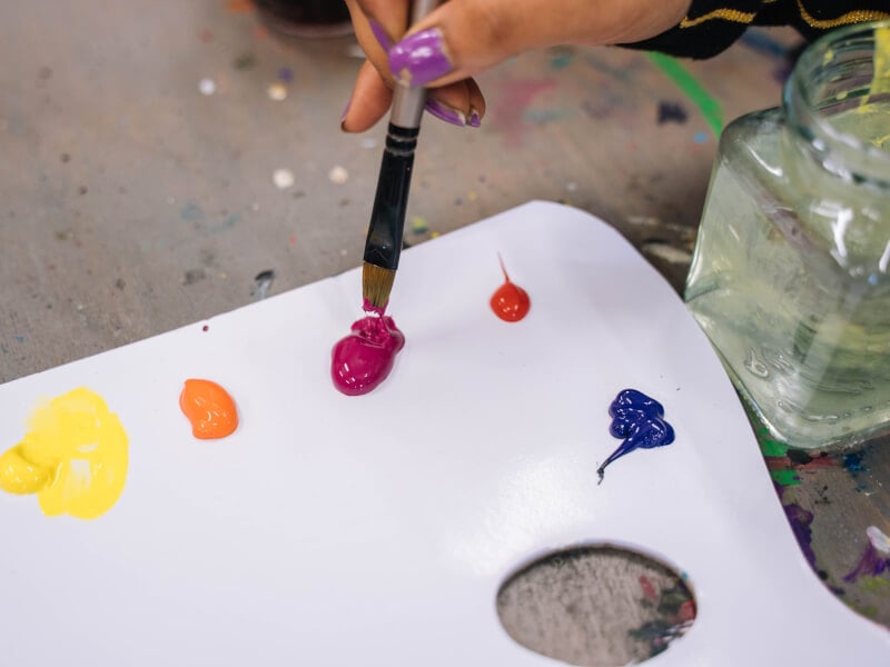 A closeup of a brush being dipped in paint at an art class.
